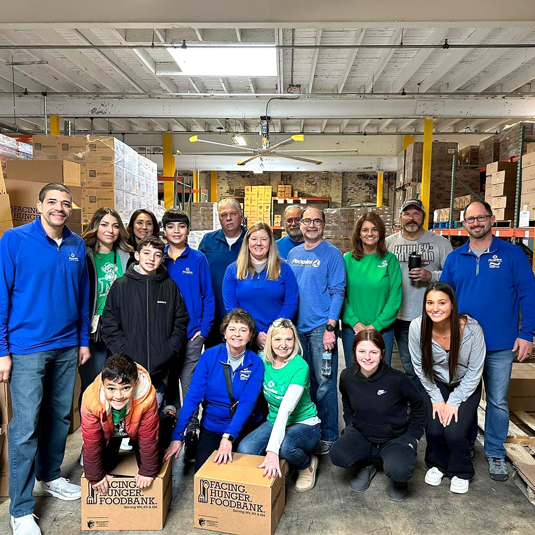 Seventeen Peoples Associates and family members pose in the Facing Hunger Foodbank warehouse